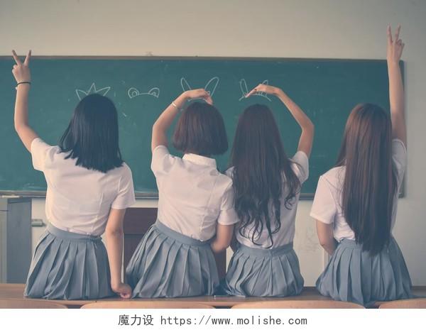 毕业季背景毕业季穿校服的四个女孩手比背景图片